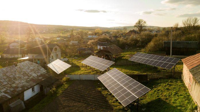 Aerial top down view of solar panels in green rural village yard. Green energy