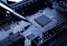 Importance of the Tallebung Tin Project to the renewable energy market The hand holding the tin, a soldering iron solder the chip in place. Computer repair. Macrophotography.