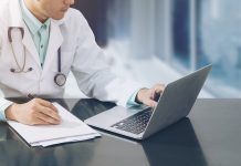 Doctor,Working,With,Laptop,Computer,And,Writing,On,Paperwork.,Hospital,AI,in,Healthcare