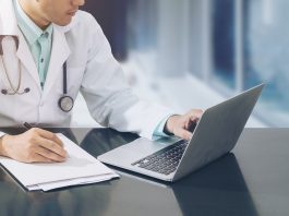 Doctor,Working,With,Laptop,Computer,And,Writing,On,Paperwork.,Hospital,AI,in,Healthcare