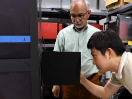 Lead muon detector developer Polad Shikhaliev looks on as JungHyun Bae, a Wigner Distinguished Staff Fellow at ORNL, looks inside a muon detector he envisioned during his doctoral studies. Credit: Sumner Brown Gibbs/ORNL, U.S. Dept. of Energy